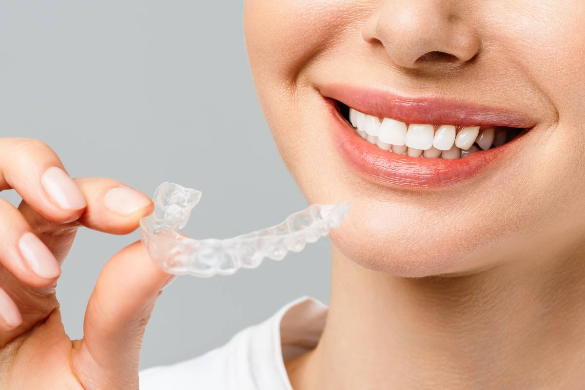 A young woman holding clear aligners.